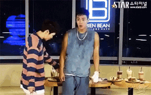 two men are standing in front of a sign for bien bean