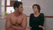 a man without a shirt is standing next to a woman