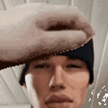 a man wearing a black beanie is holding his hand over his forehead .