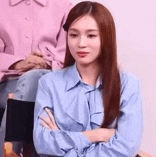 a woman with long hair is sitting in a chair with her arms crossed .