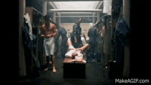 a man laying on a bench in a locker room with makeagif.com on the bottom right