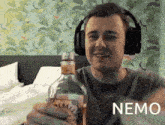 a man wearing headphones is holding a bottle of beer and the word nemo is on the bottom