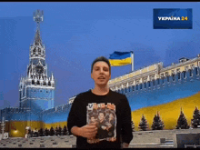 a man wearing a vlad-an shirt stands in front of a large building
