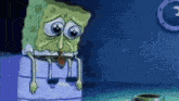 spongebob squarepants is crying while sitting on a box in a room .