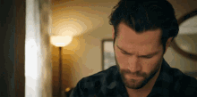 a man with a beard is looking down in a room