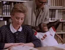 a chimpanzee wearing a red sox shirt sits next to a woman