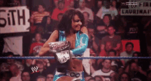 a woman is standing in a wrestling ring with a sign that says 5th