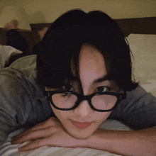 a person wearing glasses laying on a bed