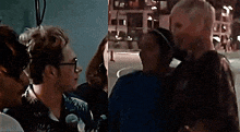 a group of people are standing next to each other on a city street at night .