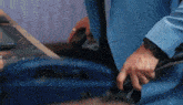 a man in a blue suit is cutting a piece of paper with a pair of scissors .