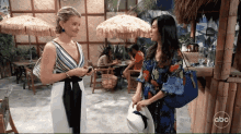 two women standing next to each other in front of a abc logo