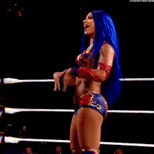 a woman with blue hair is standing in a wrestling ring and laughing