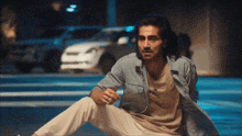 a man in a denim shirt is sitting on the ground