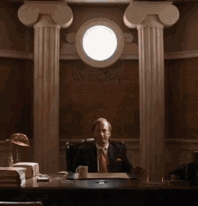 a man in a suit and tie is sitting in a chair in front of a painting of a man .