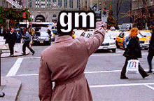 a man in a trench coat holds up a sign that says " gm "