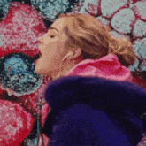 a woman wearing ear buds is singing in front of a wall of berries