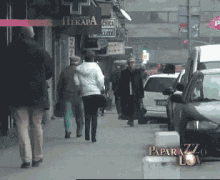 people walking down a street with a paparazzi logo