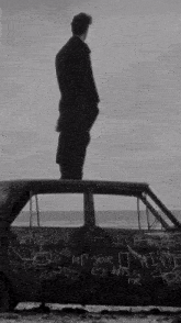 a man is standing on top of a car with graffiti on it