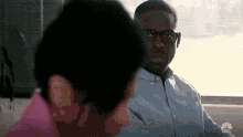 a man wearing glasses is sitting next to a woman in a room .