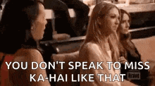 three women are sitting next to each other on a couch and talking to each other .