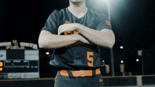 a baseball player stands with his arms crossed in front of a scoreboard that says smith field