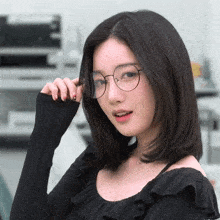 a woman wearing round glasses and a black top