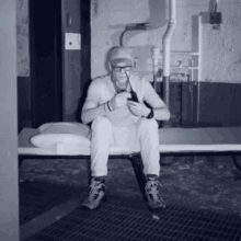 a man wearing glasses and a hat sits on a bench in a dark room