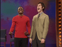 a man in a red shirt is standing next to another man in a suit