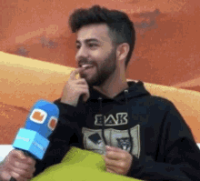 a man wearing a black eak sweatshirt holds a microphone