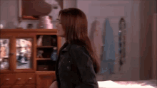 a woman in a black jacket stands in a room