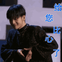 a man in a black jacket is making a heart shape with his hands