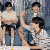 a group of young men are sitting on a couch and applauding .