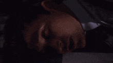 a man in a suit and tie is laying on the floor with his eyes closed and blood on the floor .