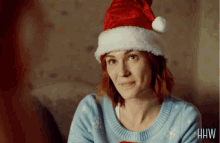 a woman wearing a santa hat and a blue sweater with the letters hw on the bottom