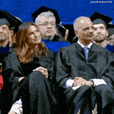 a woman in a graduation gown sits next to a man in a graduation cap and tie