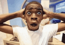 a man in a white shirt is making a surprised face with his hands on his head