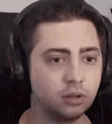 a close up of a man wearing headphones making a funny face .