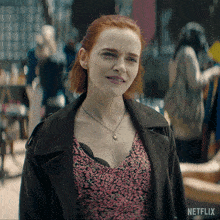 a woman with red hair is wearing a necklace and a netflix advertisement