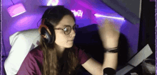 a woman wearing headphones and glasses is sitting in front of a computer monitor .