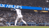 a baseball player is swinging at a ball in front of a banner for ux airlines
