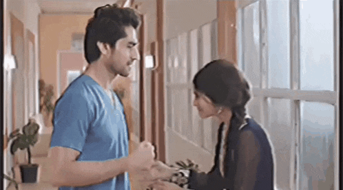 a man and a woman are standing next to each other in a hallway .