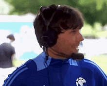 a man wearing headphones and a blue shirt with a soccer ball on the front