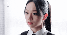 a close up of a woman 's face with a ponytail and earrings .