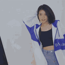 a blurry picture of a woman wearing a blue and white jacket and a black crop top .