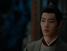 a man in a traditional costume is standing in a dark room and looking at the camera .