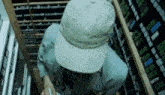 a man wearing a hat and a blue shirt is standing in a room filled with shelves .