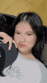a young girl with long black hair is sitting in a car and taking a picture of herself .