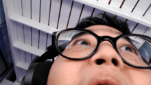a man wearing glasses and headphones looks up at something