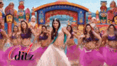 a woman in a white dress is dancing in front of a group of women