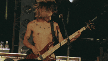 a shirtless man playing a guitar with the letter d in the lower right corner